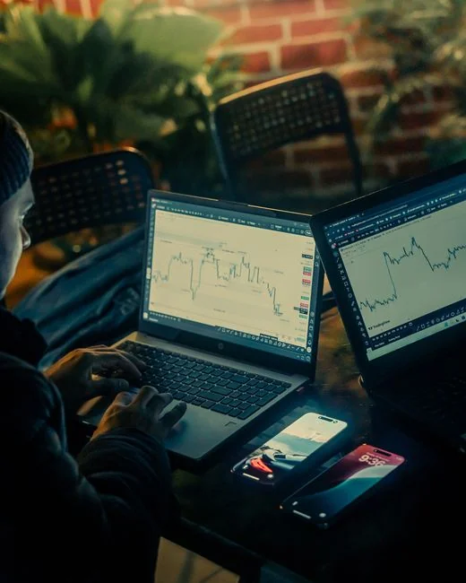 about-us-02 Person analyzing business charts with smartphone and laptop on desk.